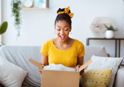 Happy girl unpacking clothes after online shopping