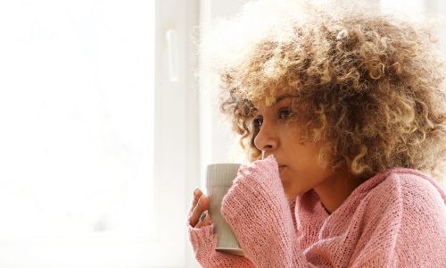 young african american woman drinking hot cup of coffee in the morning