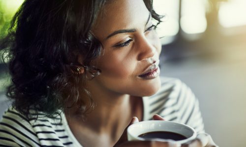 Young African woman drinking a coffee looking deep in thought